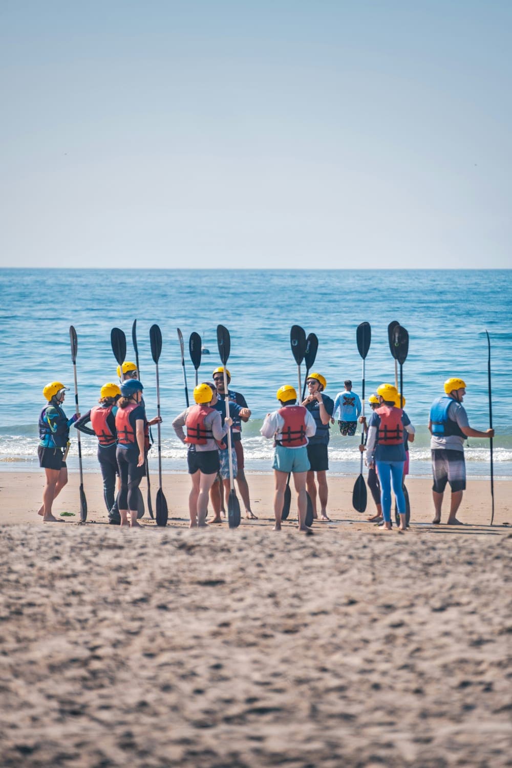 A group gathered on the beach with kayaks before setting out together
